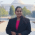 Professional woman standing outdoors in front of auditorium building.